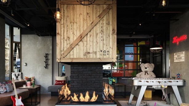 A cozy room with a fireplace, a table with a teddy bear, and a neon sign. - Moxy Belgrade (Belgrade)