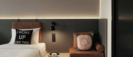 A modern bedroom with a bed, bedside table, and a nightstand with a telephone.