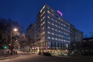 Ein mehrstöckiges Hotel mit modernem Design, das ein markantes Neonzeichen auf dem Dach zeigt.