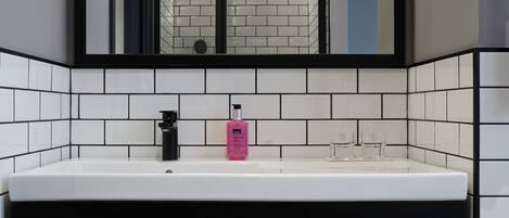 A modern bathroom with a white sink, black frame, and tiled walls.