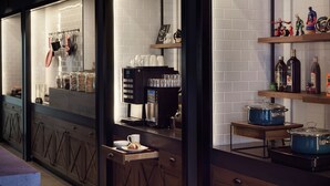A modern kitchen with a coffee machine, jars of spices, and a shelf with small figurines. - Moxy Belgrade (Belgrade)