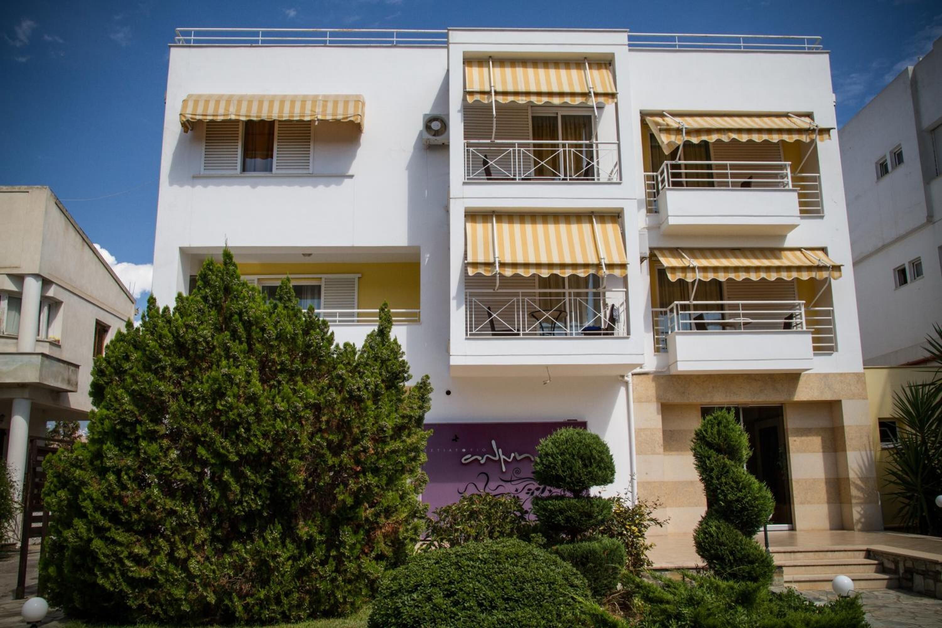 Un edificio a più piani con balconi, un giardino e un cartello con il nome "Antonia".