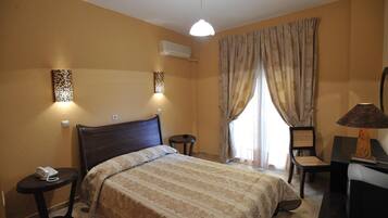 A hotel room with a bed, bedside tables, a desk with a chair, a lamp, and curtains.