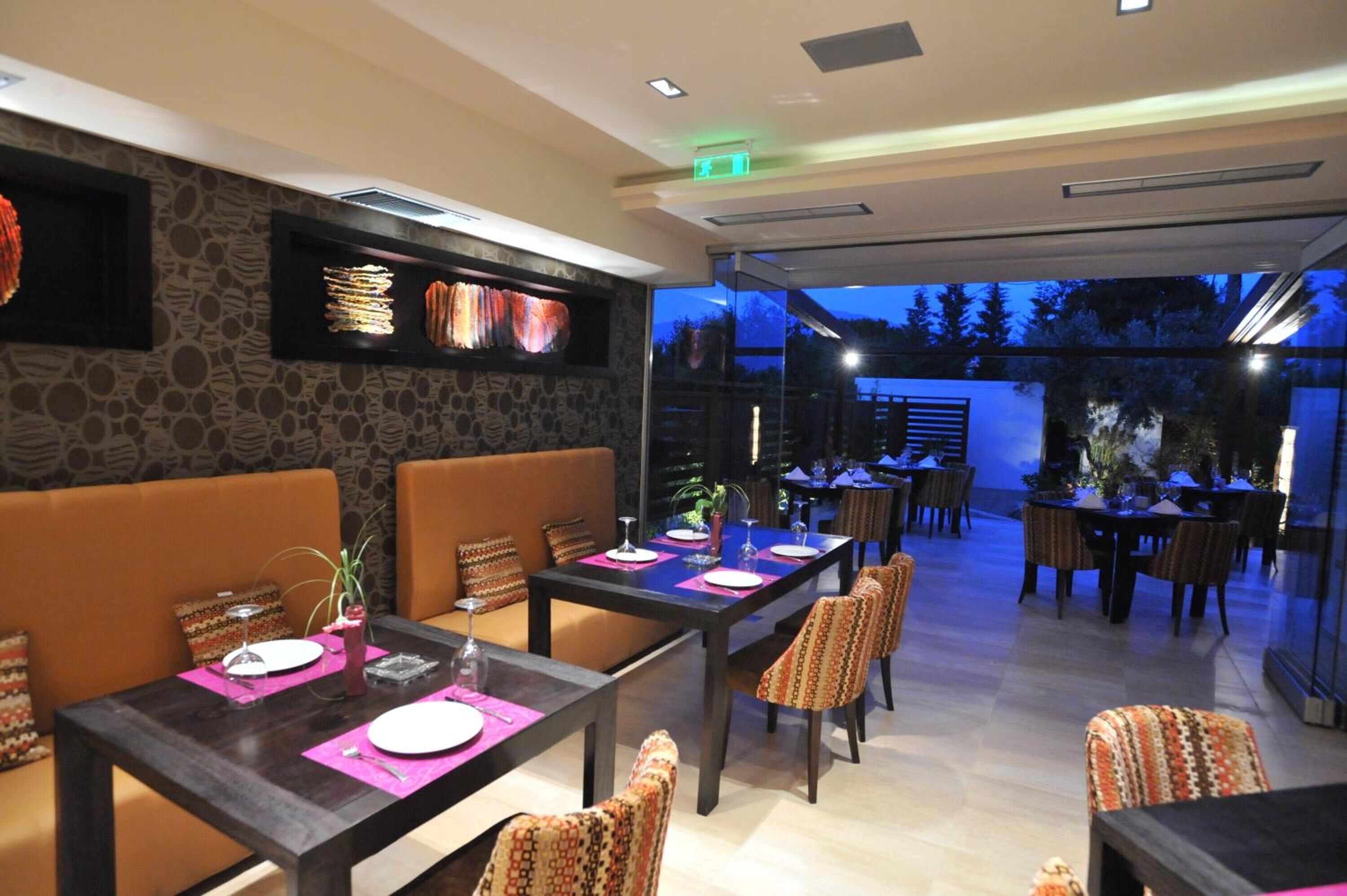 A restaurant with tables set for dining, a stone wall, and a view of the outdoors.