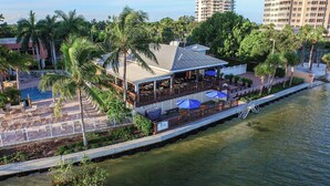 Un restaurante frente al agua con terraza al aire libre, porche cubierto y vista al mar.