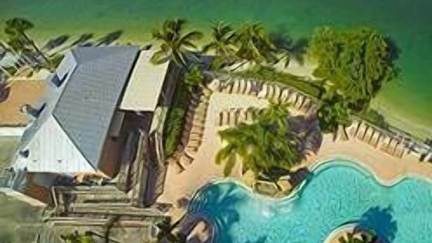 Un resort con piscina, palmeras y vista al océano.