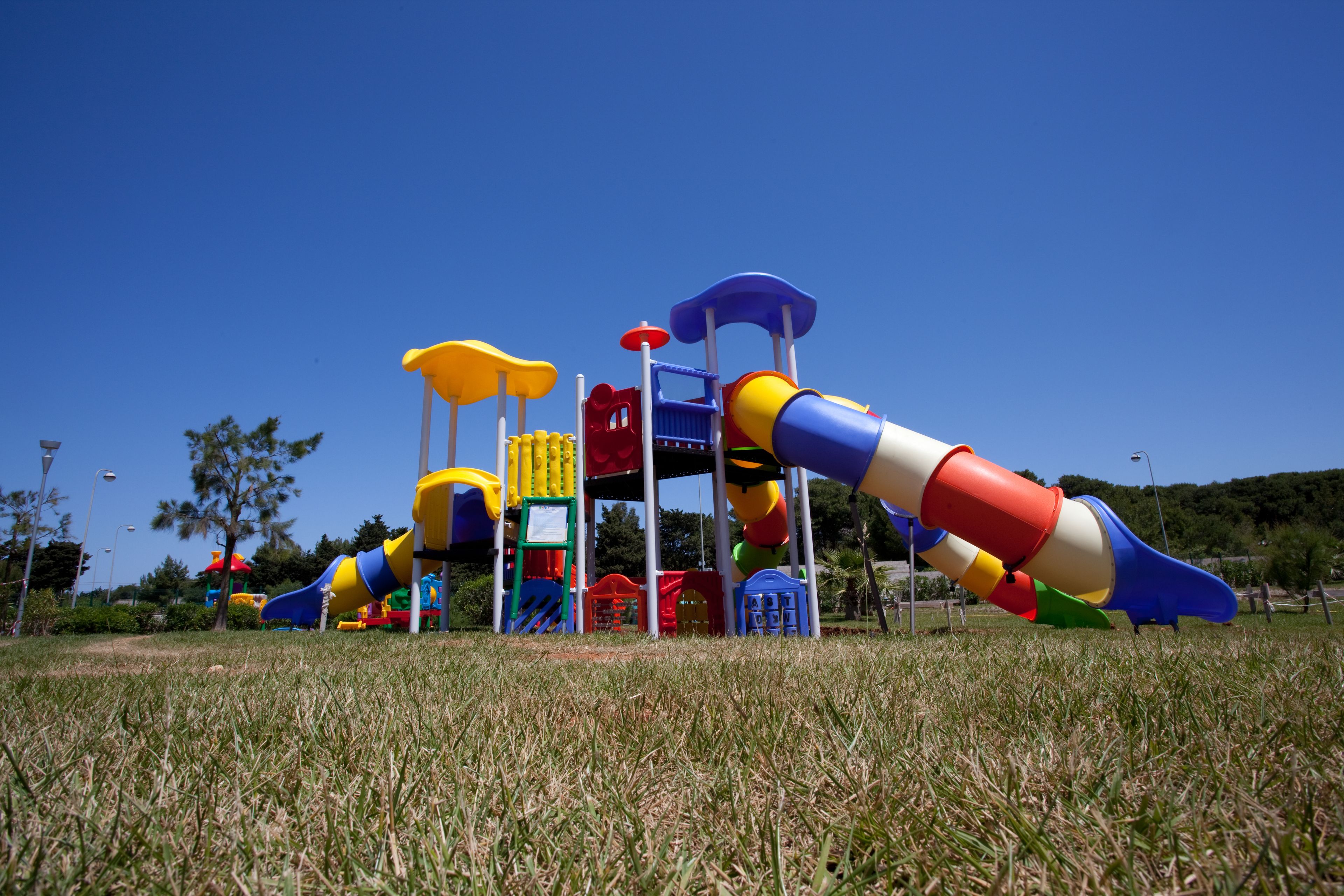 Ein Spielplatz mit Rutschen und Klettergerüsten in einer grünen Wiese.