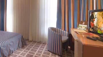 Een hotelkamer met een bed, een stoel, een bureau en een televisie.