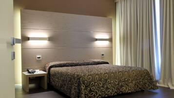 Habitación de hotel con una cama grande, mesita de noche y cabecero con iluminación integrada.