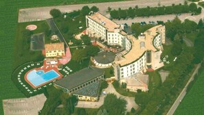 Vista aérea de un complejo hotelero con varias construcciones, piscina y abundante vegetación.