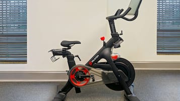 An exercise bike with a digital display, positioned in a room with windows and a carpeted floor.