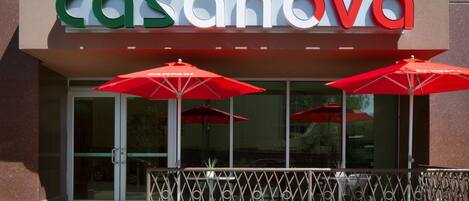 A restaurant named "Ristorante Casanova" with a modern facade, large glass windows, and red umbrellas outside.