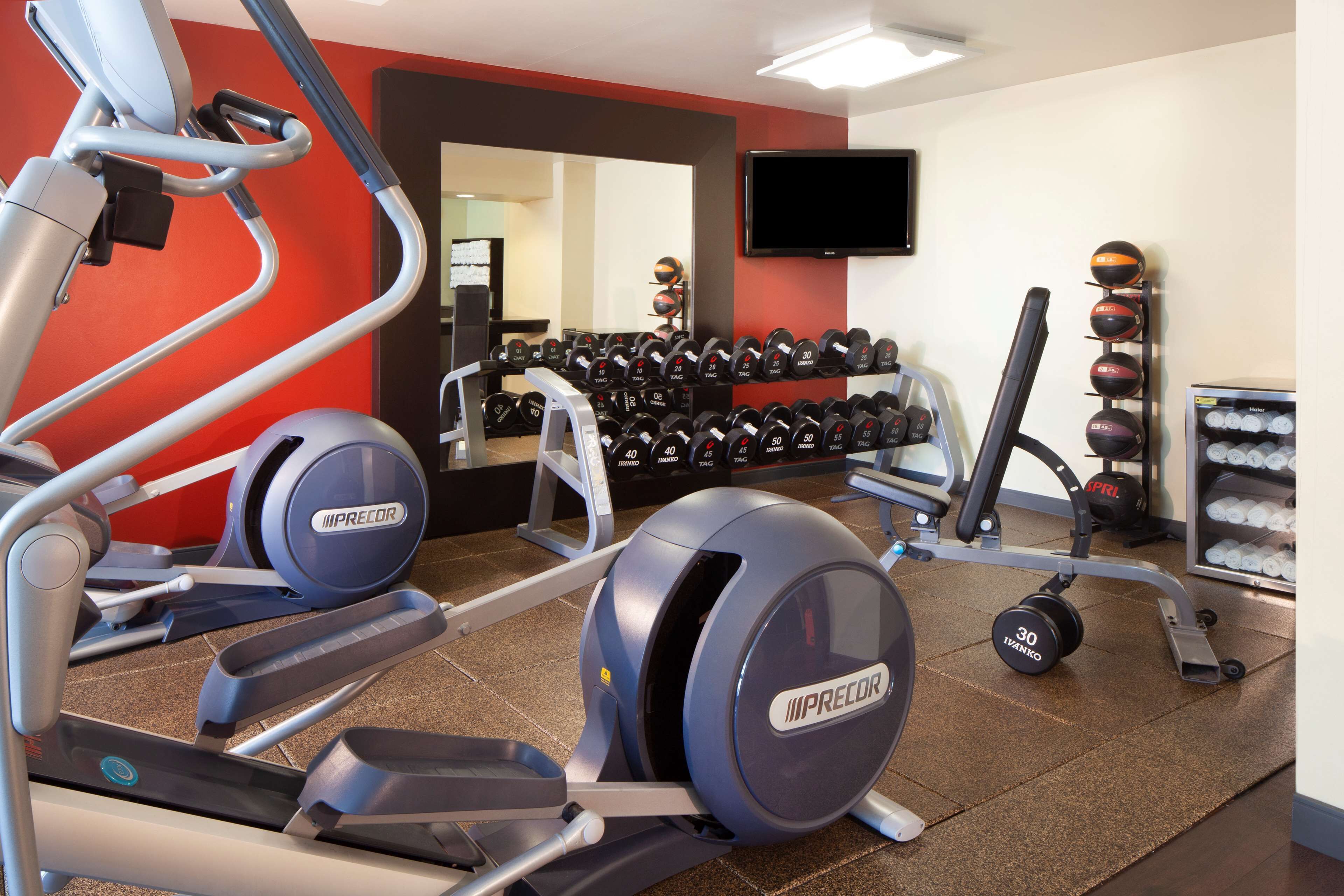 Ein Fitnessraum mit Laufbändern, Hanteln und Trainingsgeräten.