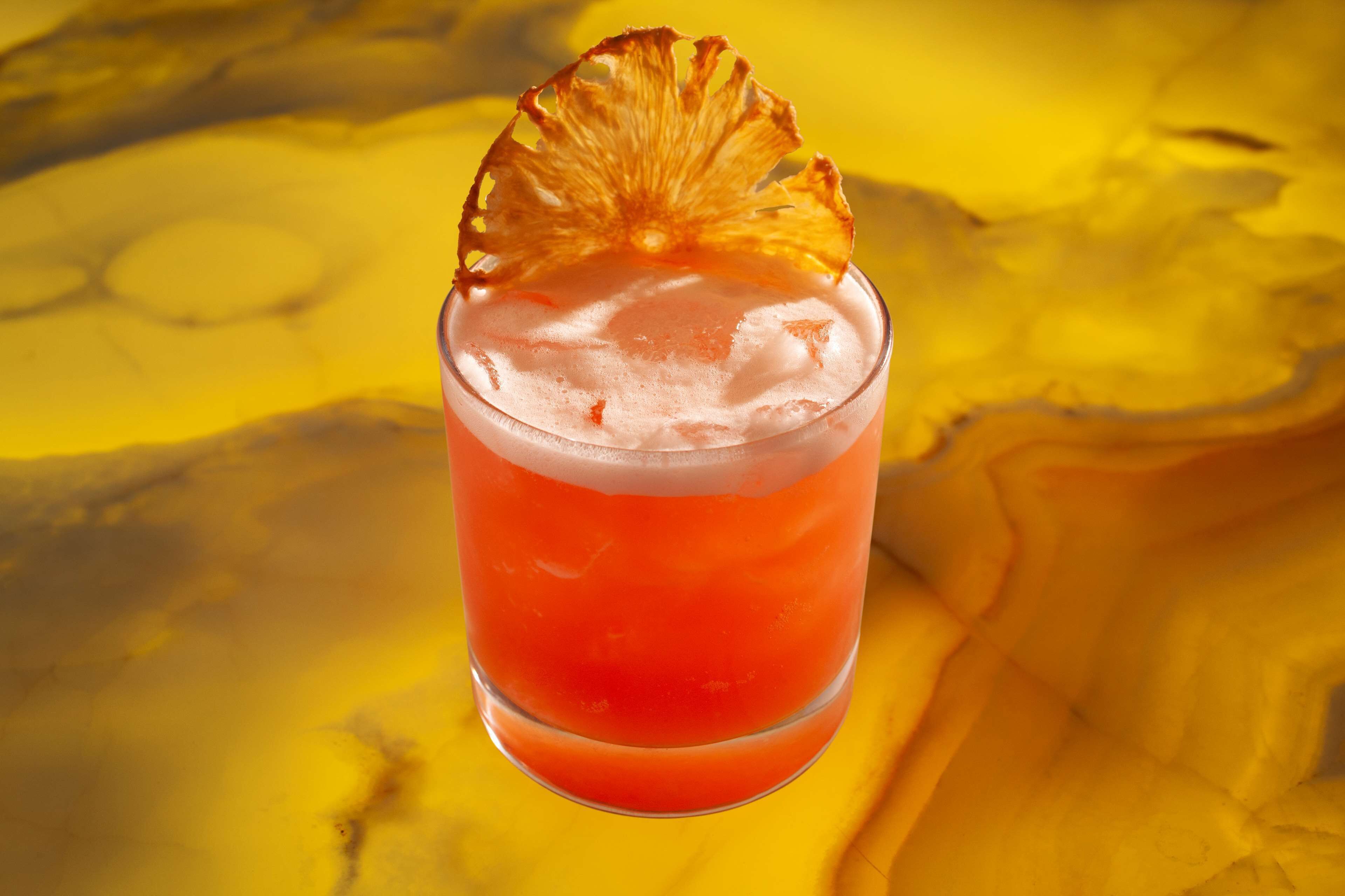 Een cocktail met een ananasdecoratie in een glas.