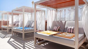 Two outdoor lounge chairs with white frames and grey cushions, under a wooden pergola, with sheer curtains and a clear sky in the background. - DoubleTree by Hilton El Paso Downtown (El Paso)