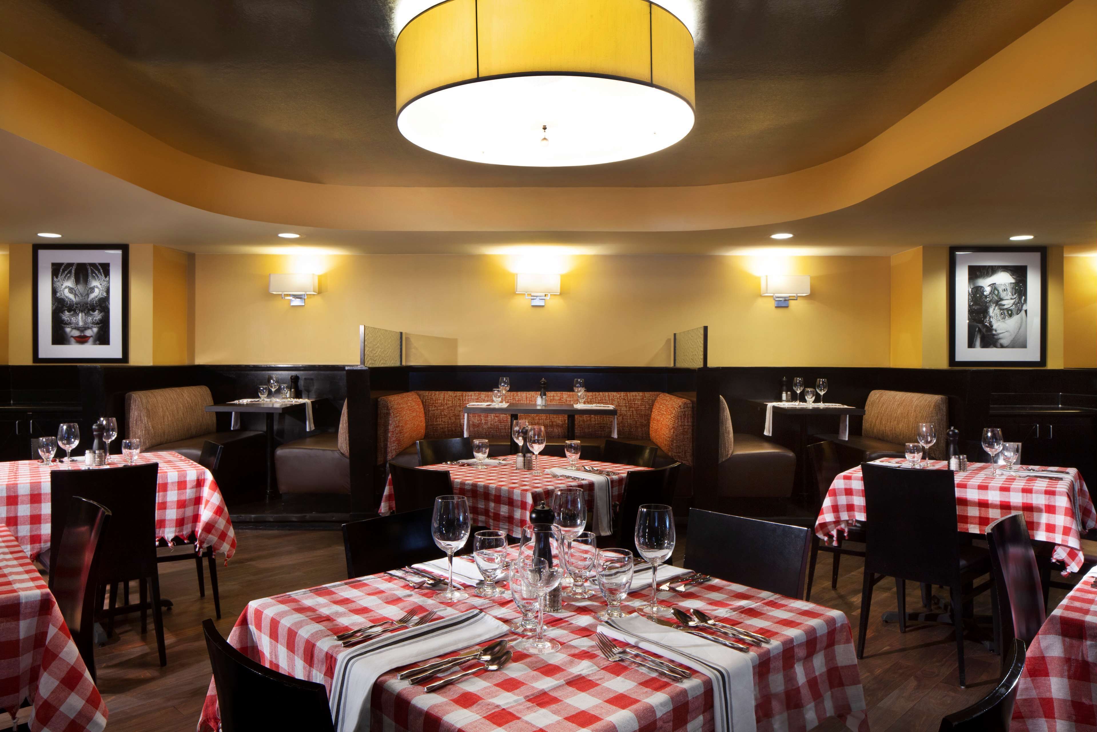 A restaurant with checkered tablecloths, round tables, and cushioned booths.