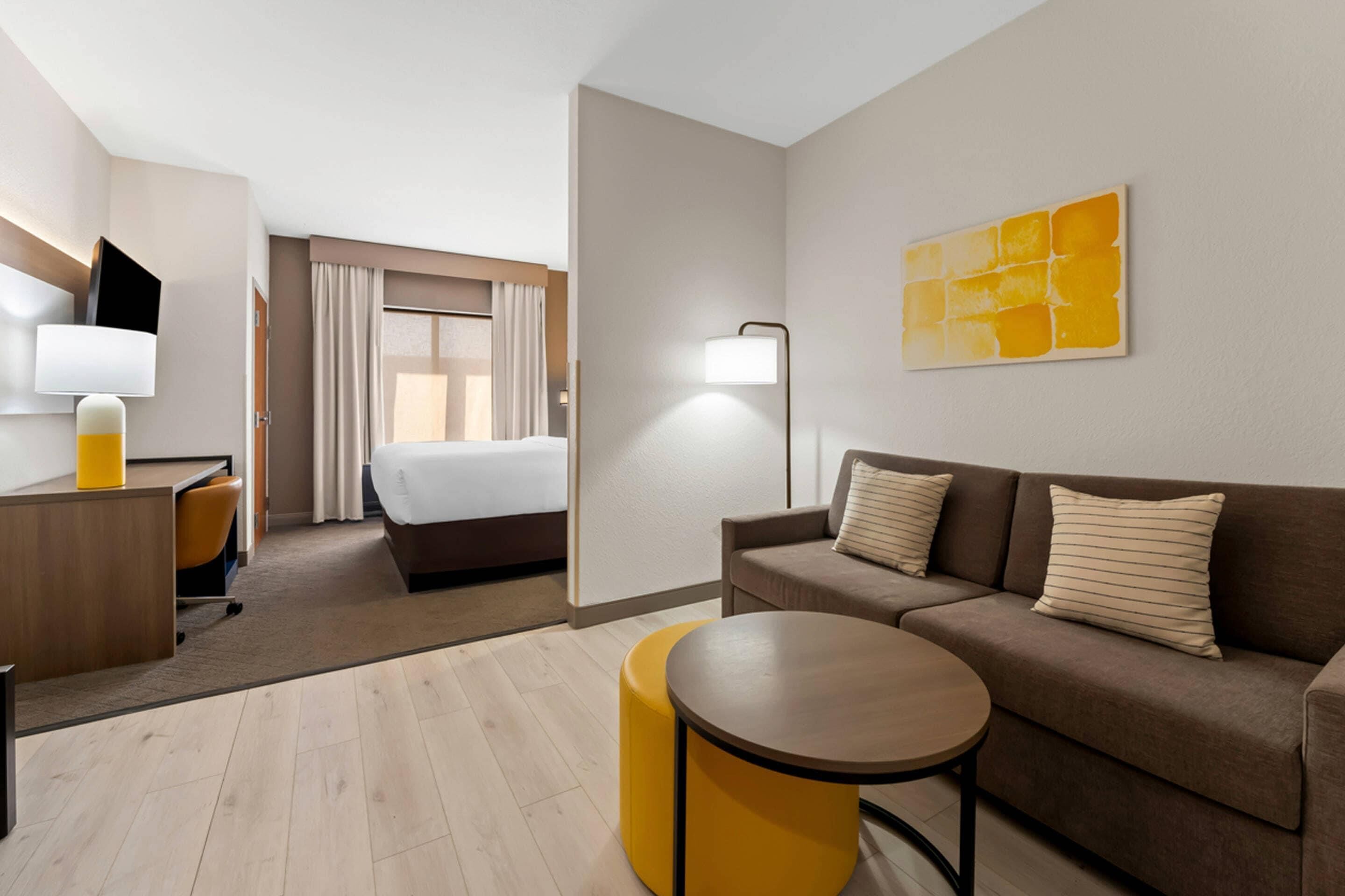 Een hotelkamer met een bed, een slaapbank, een bureau met lamp en een klein rond tafeltje.