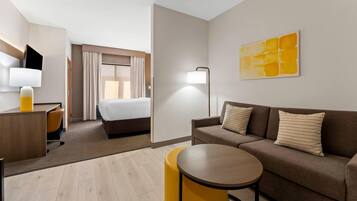 Een hotelkamer met een bed, een slaapbank, een bureau met lamp en een klein rond tafeltje.