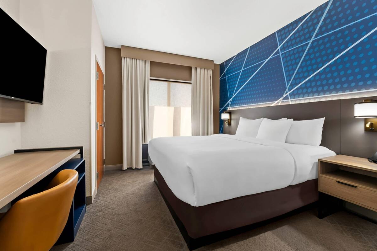 Una habitación de hotel con cama, escritorio, silla y televisor.