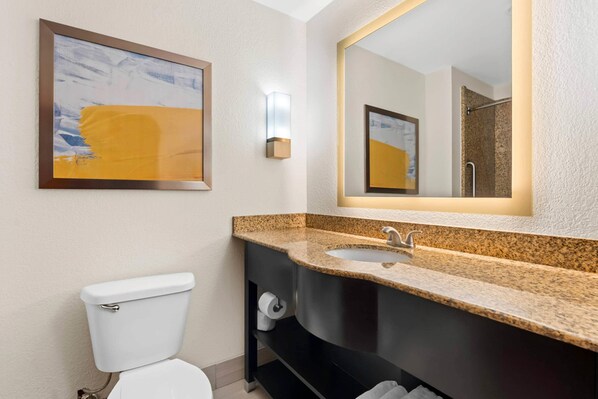A bathroom with a toilet, a sink, a mirror, and a framed abstract painting on the wall. - Comfort Suites Augusta Riverwatch (Augusta)