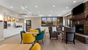A modern dining area with a kitchen, a fireplace, and a large TV screen. - Comfort Suites Augusta Riverwatch (Augusta)