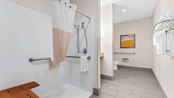 Une salle de bain moderne équipée d’une douche, de toilettes et d’un banc en bois.