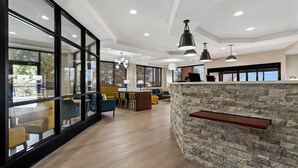 A modern interior with large windows, a stone accent wall, and a dining area with yellow chairs. - Comfort Suites Augusta Riverwatch (Augusta)