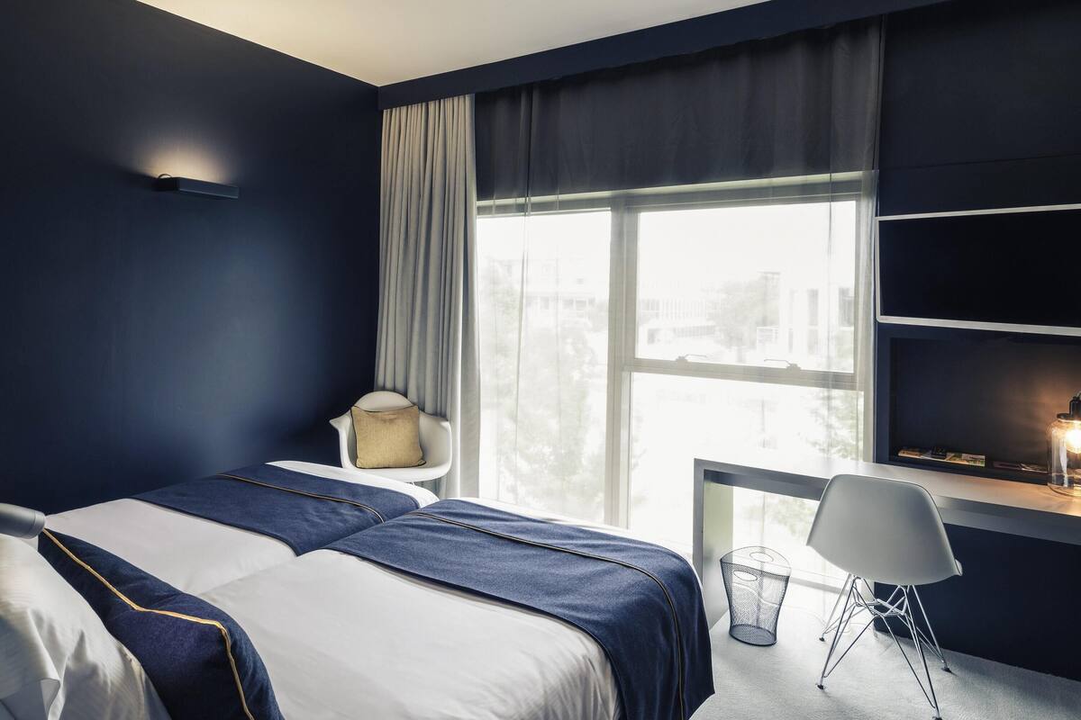 Ein modernes Hotelzimmer mit einem großen Bett, einem Schreibtisch und einem Stuhl.