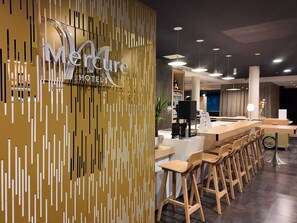 A modern hotel lobby with a bar area, bar stools, and a reception desk. - Hôtel Mercure Nantes Ouest Saint-Herblain Zenith (Saint-Herblain)