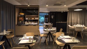 A modern dining area with tables and chairs, a bar counter, and a view of the outdoors. - Hôtel Mercure Nantes Ouest Saint-Herblain Zenith (Saint-Herblain)