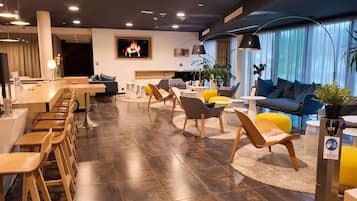 A modern hotel lobby with a dining area, seating arrangements, and a fireplace.