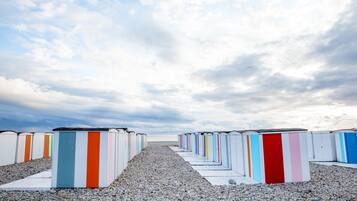 En række strandhuse med en grussti, der fører hen til dem, under en overskyet himmel.