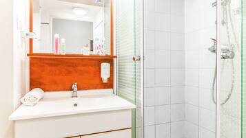 Ein Badezimmer mit Waschbecken, Holzschrank und Duschkabine aus Glas.