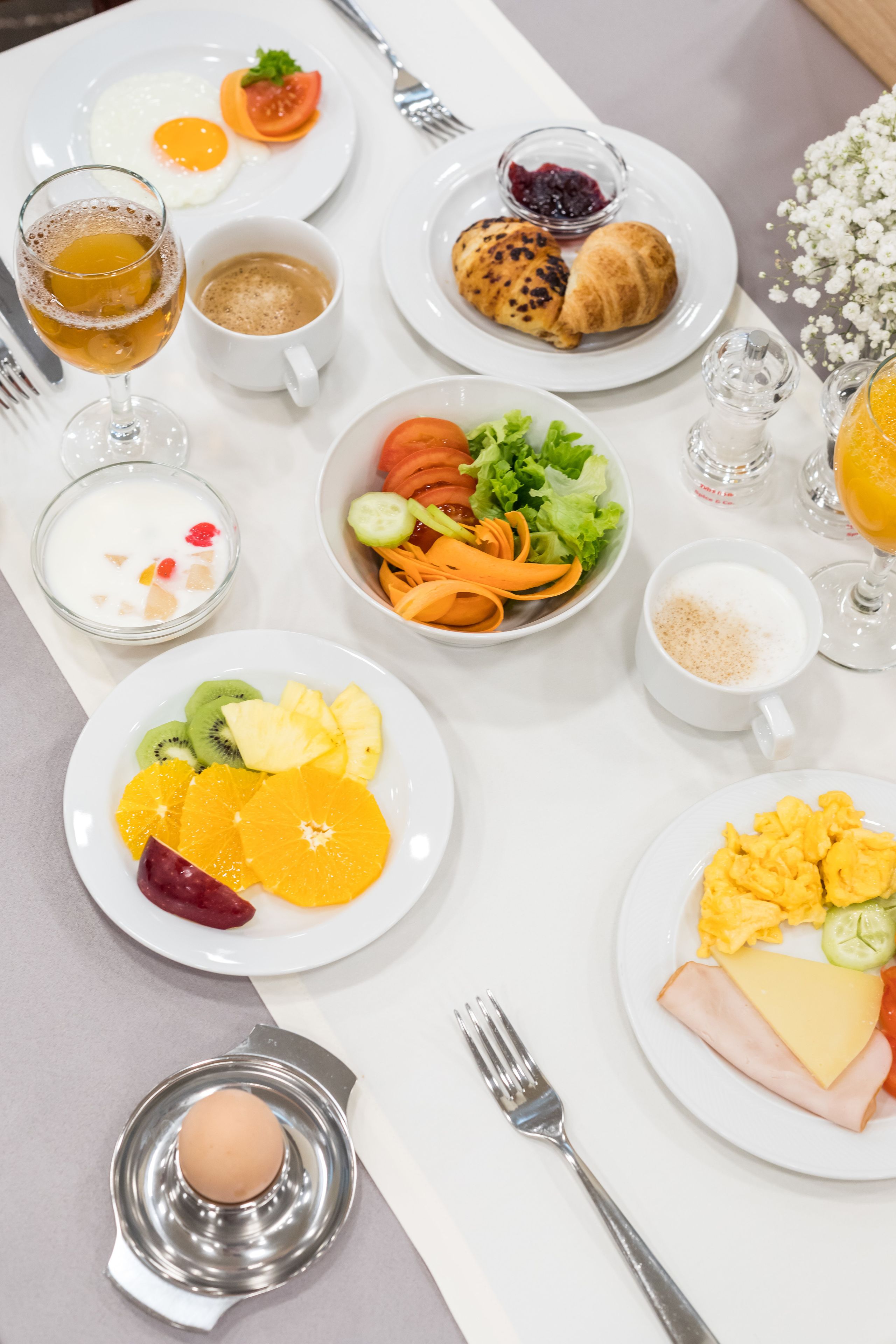 Un desayuno con diversos platos que incluyen huevos, tostadas, fruta y bebidas.