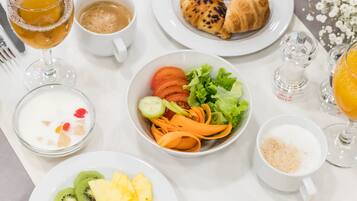 Un desayuno con diversos platos que incluyen huevos, tostadas, fruta y bebidas.