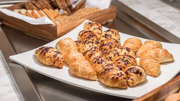 Buffet com diversos produtos de panificação, incluindo croissants e pão.