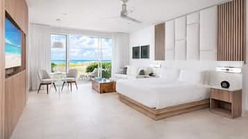 Una habitación de hotel moderna con una cama grande, un escritorio, una silla y vista a la playa.