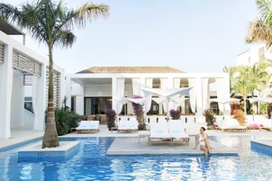 Una piscina al aire libre, sombrillas, tumbonas