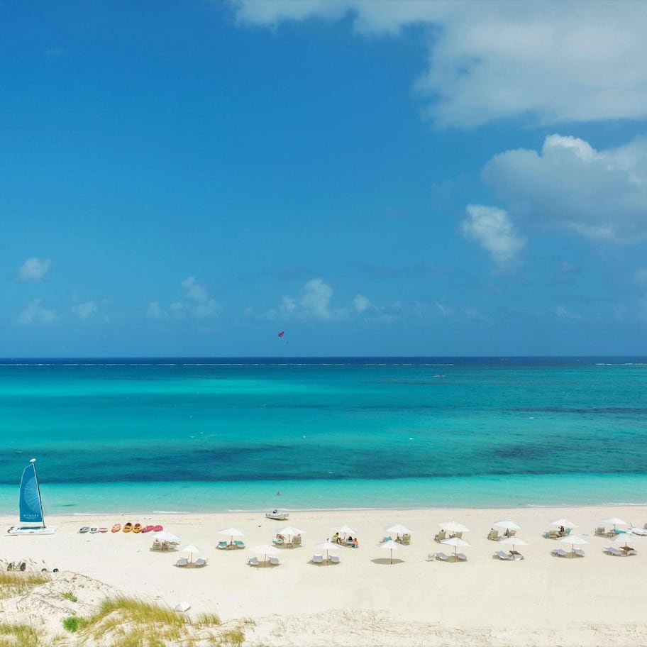 En la playa, playa de arena blanca y camas de playa (con cargo)