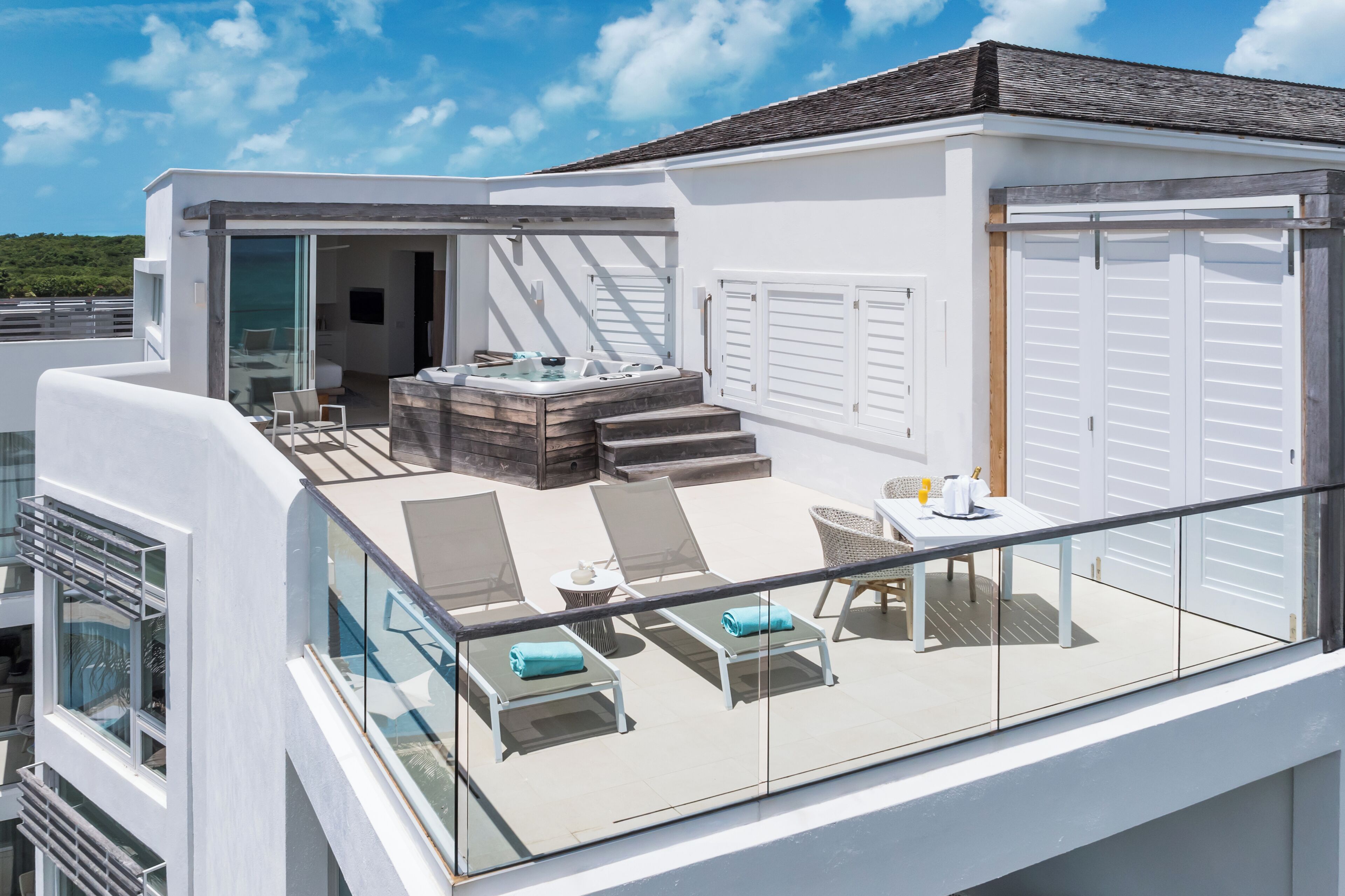 A modern rooftop deck with lounge chairs, a hot tub, and a dining area.