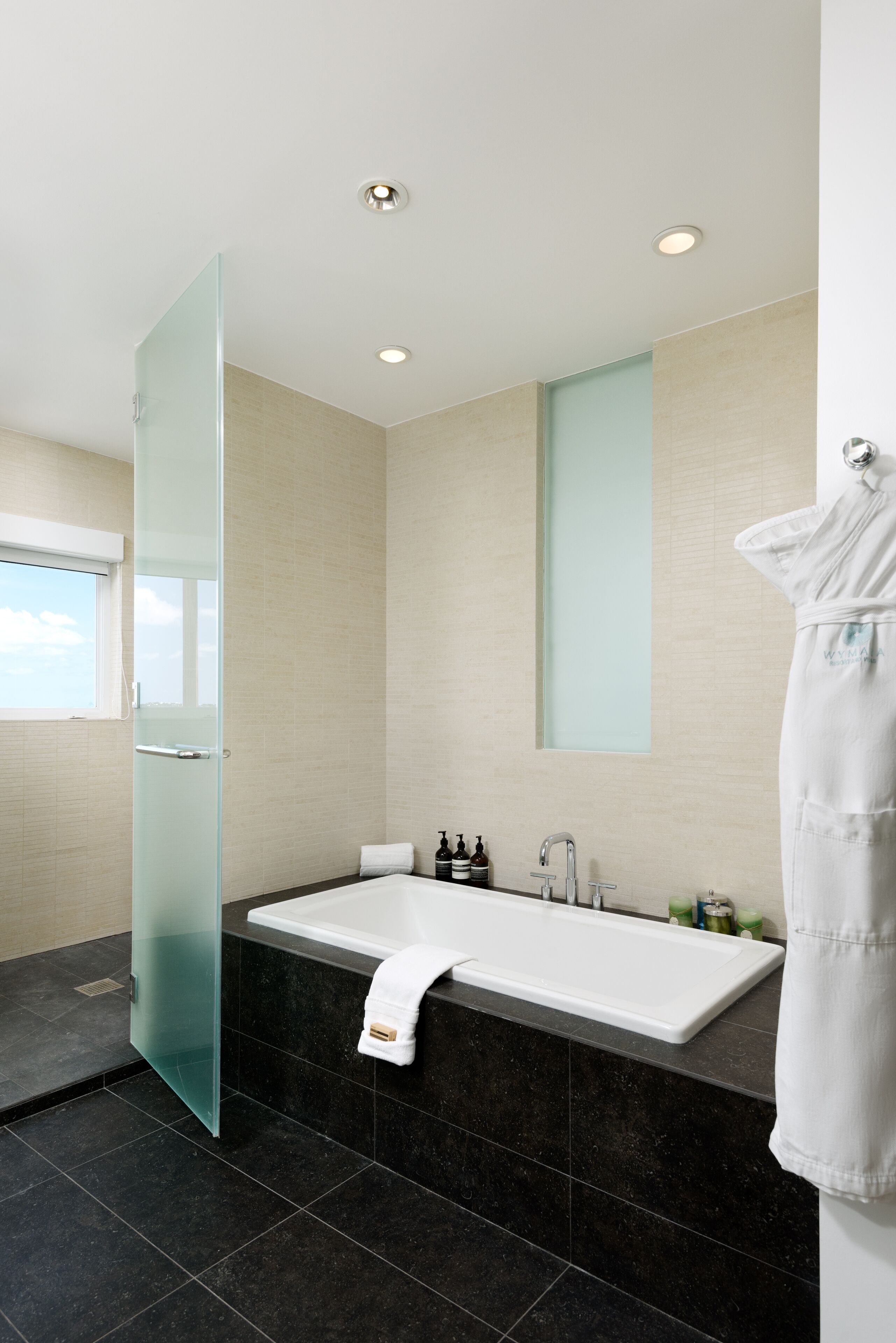 Une salle de bain moderne avec une porte de douche en verre, une grande baignoire et un porte-serviettes.