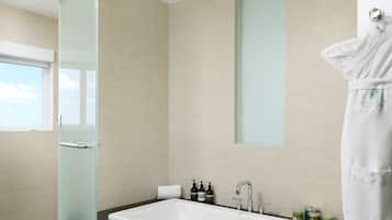 Une salle de bain moderne avec une porte de douche en verre, une grande baignoire et un porte-serviettes.