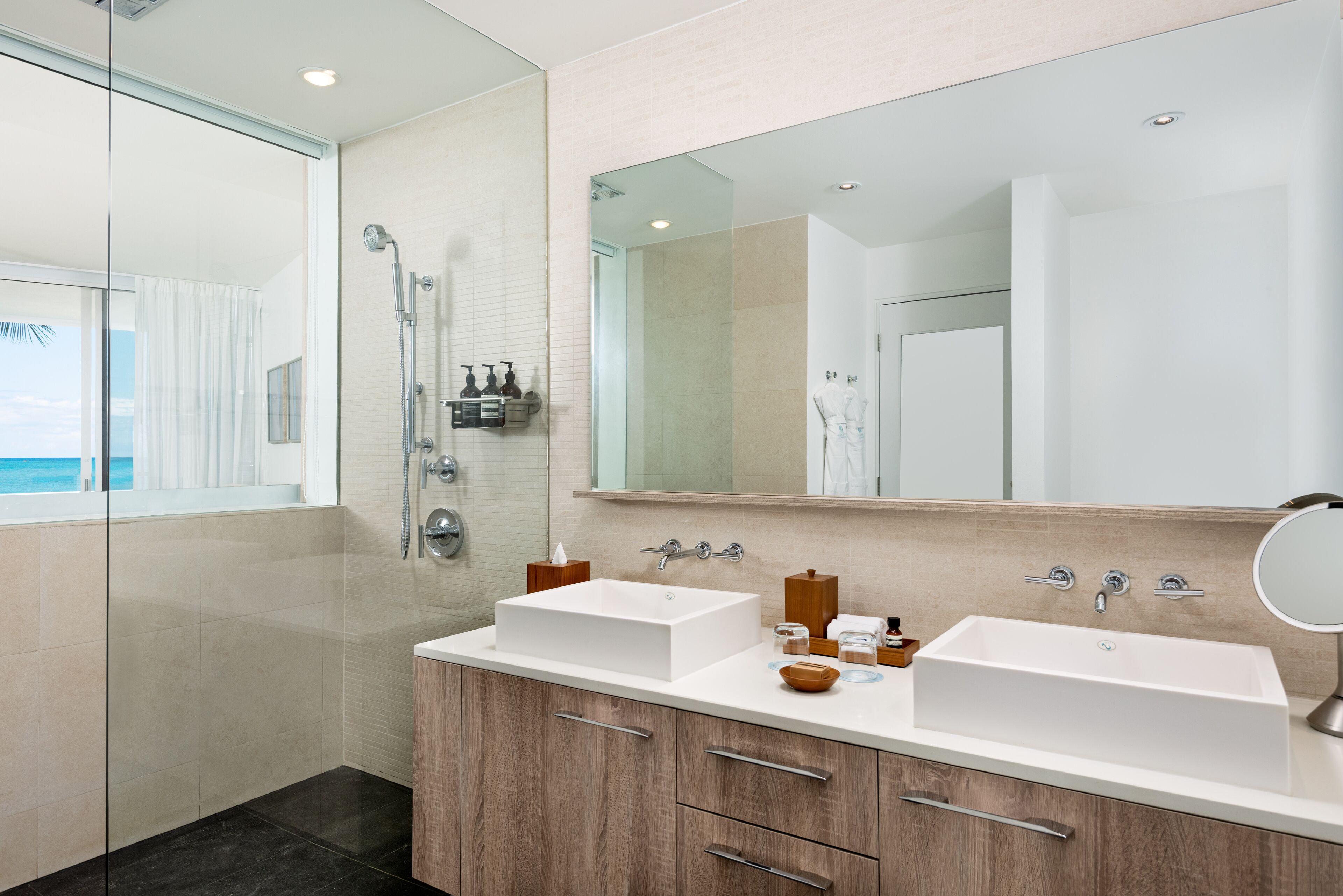 A modern bathroom with a glass shower enclosure, two sinks, and a large mirror.