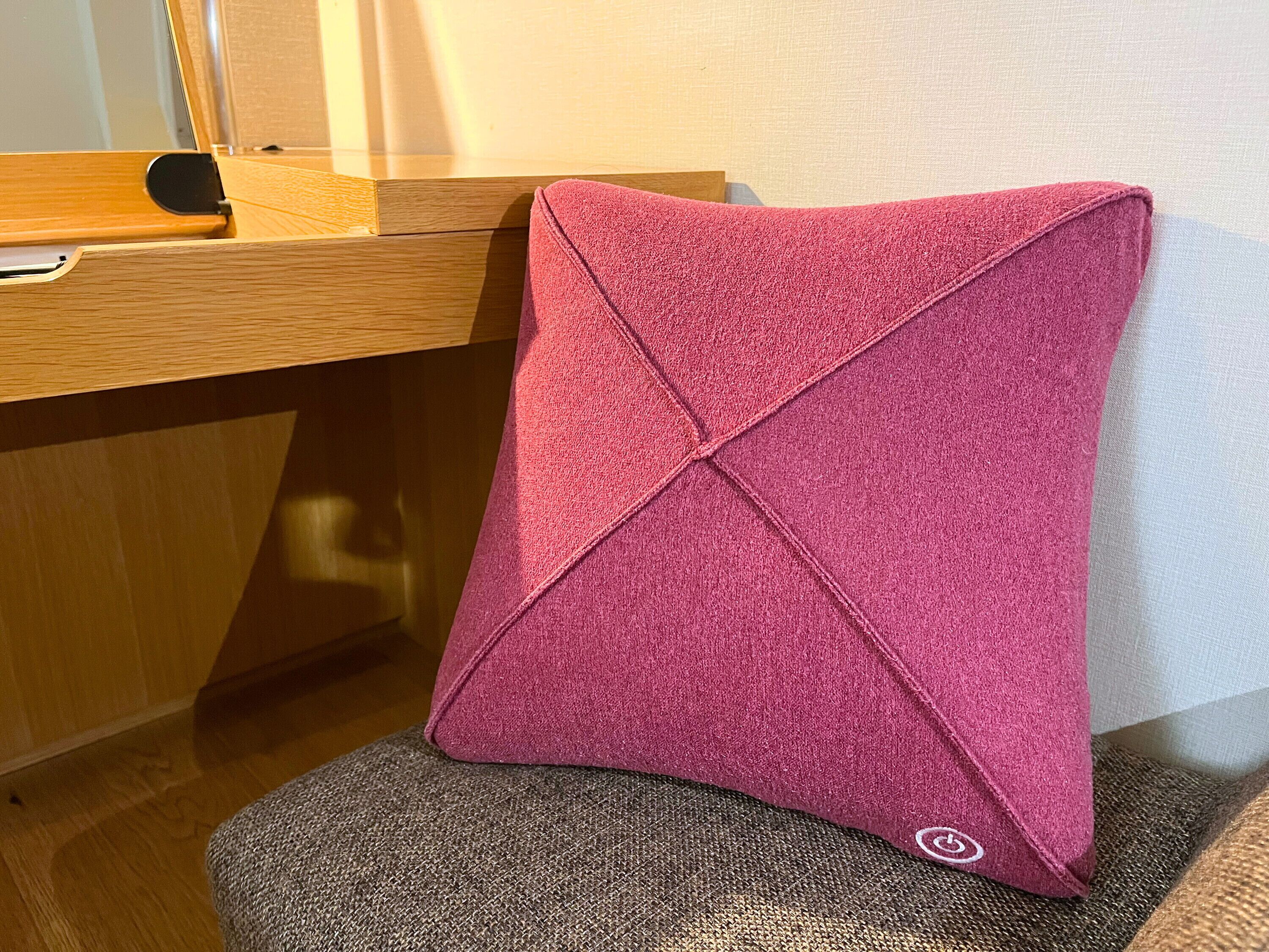 Un cojín rosa con un estampado texturizado sobre una silla.
