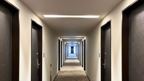A long, narrow hotel corridor with doors on both sides, a wooden floor, and overhead lighting. - Hotel Gracery Tokyo Tamachi (Tokyo)