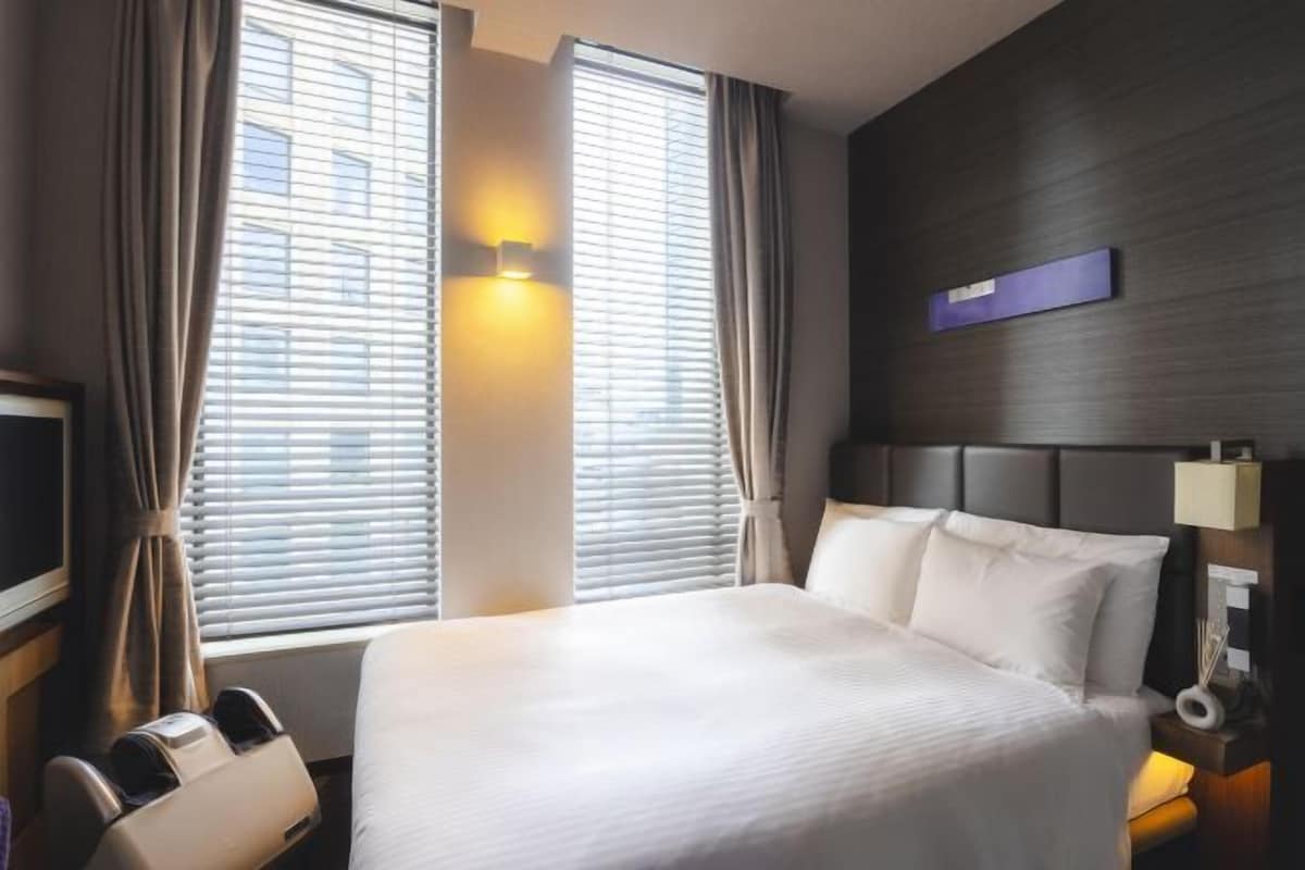 Ein Hotelzimmer mit einem großen Bett, zwei Nachttischlampen, einem Flachbildfernseher und einem Massagesessel.