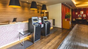 A reception area with a wooden wall, a reception desk, and three self-service kiosks. - Hotel Gracery Tokyo Tamachi (Tokyo)