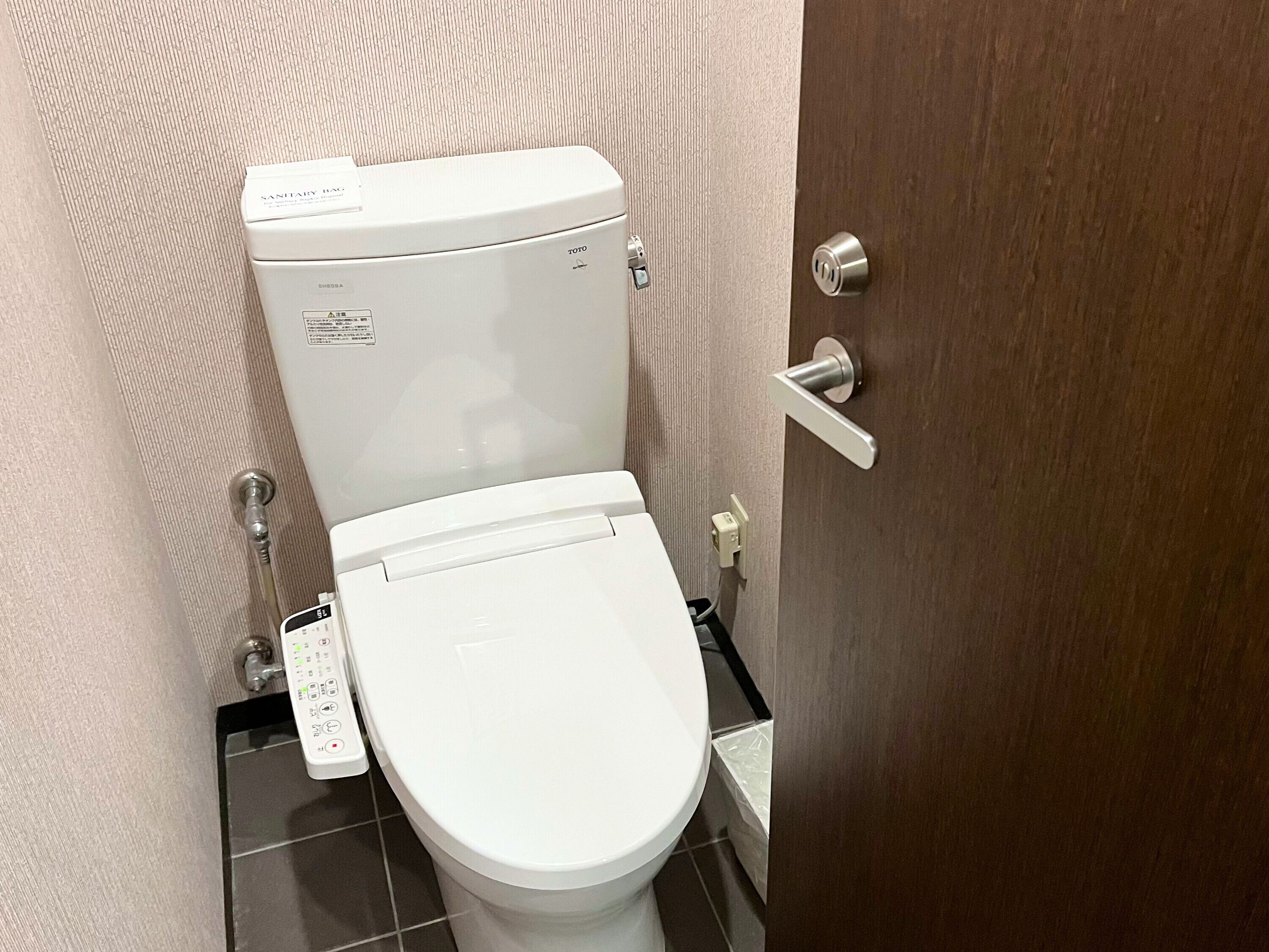A white toilet with a control panel and a toilet paper holder.