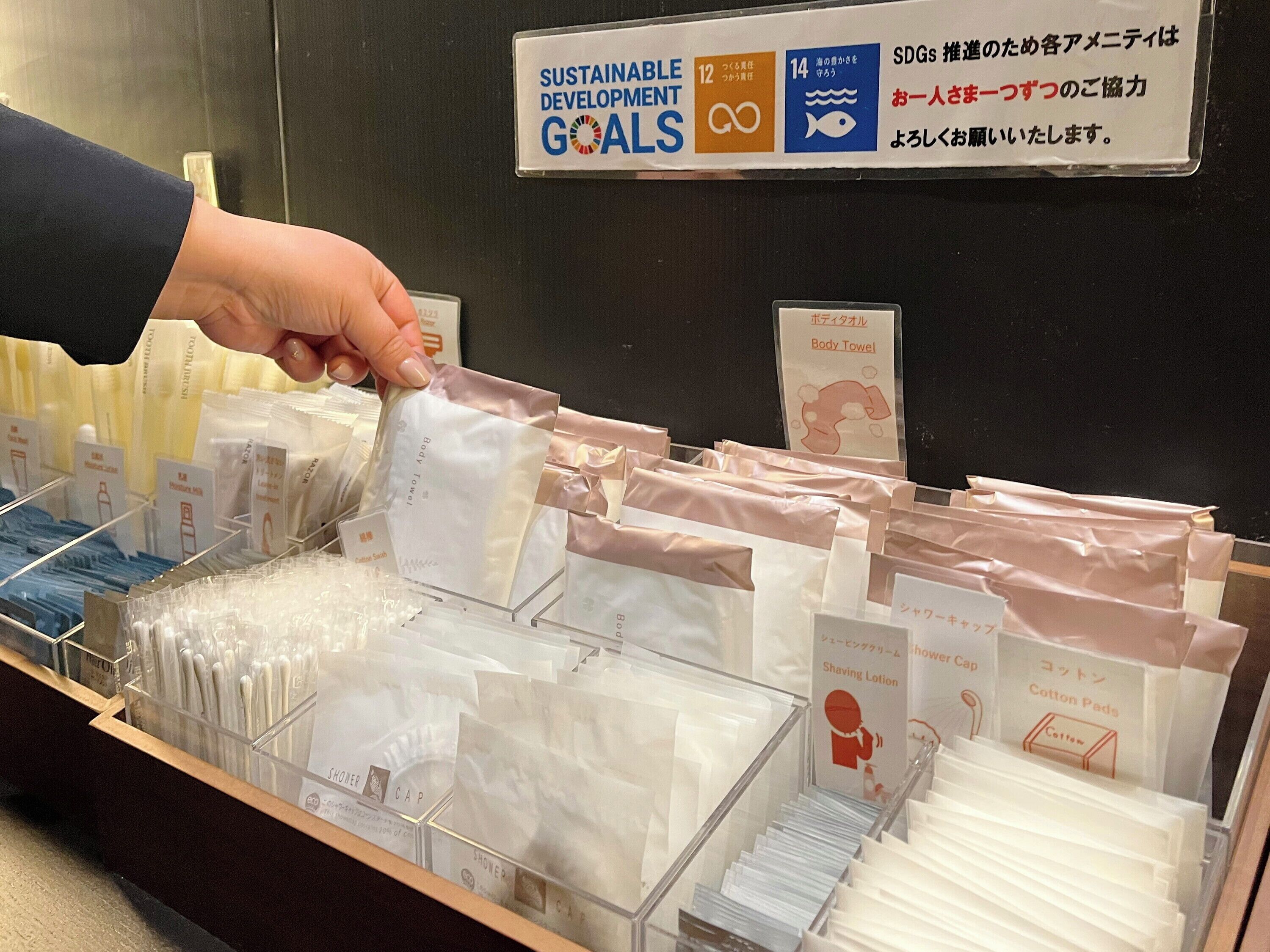 A hand selecting a body towel from a display of various toiletries.