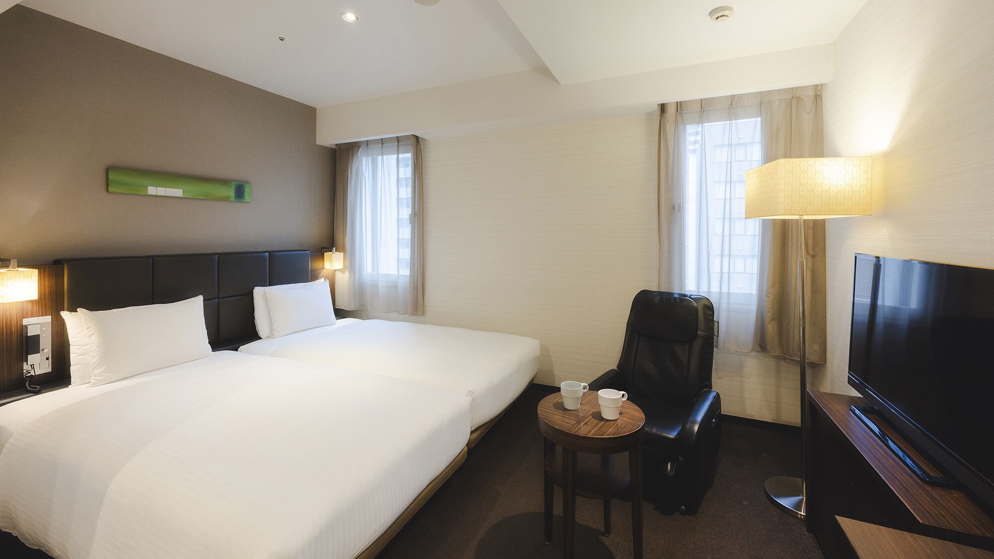 Habitación de hotel con una cama grande, un escritorio con silla, televisión y lámpara.